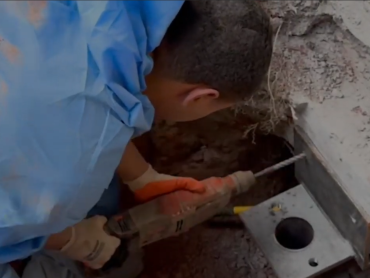 Worker installing push pier to level foundation